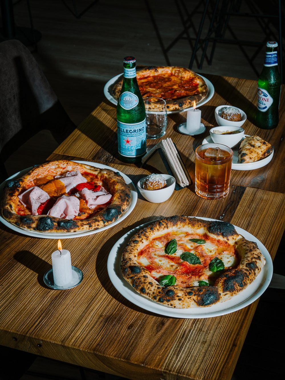 Mesa de Posdata con pizzas, arancini y bebidas a la luz de las velas